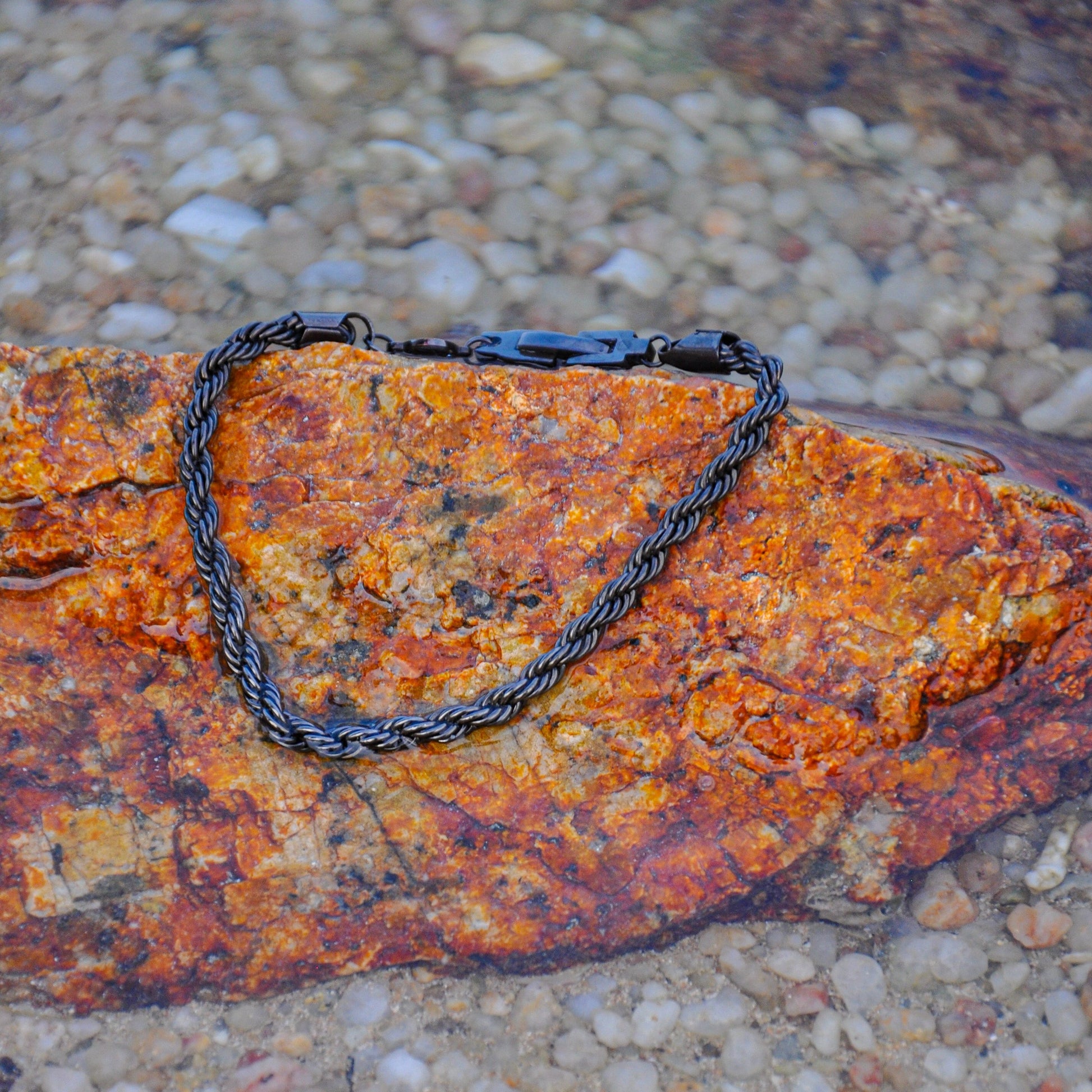 Black rope chain bracelet on rock