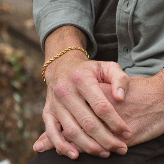 Man wrist in the woods with a gold rope chain bracelet 