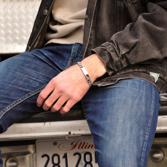 man wearing jeans black jacket and tan shirt with snowflake obsidian bracelet 